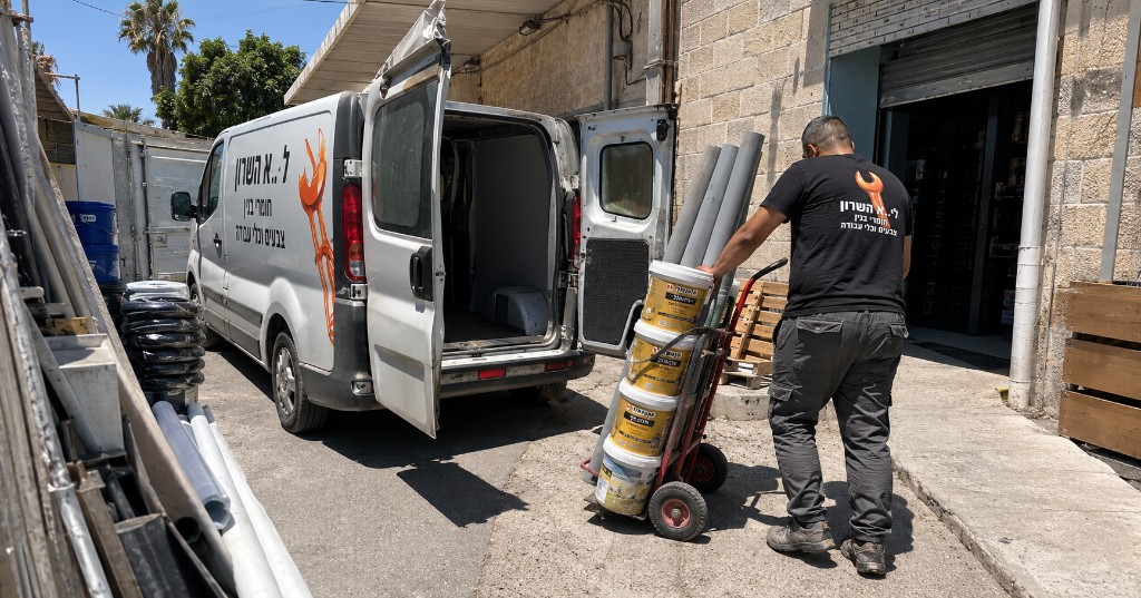 טעינת חומרי בניין לרכב משלוח — דלי צבע, צנרת ועגלה מקצועית לשטח העבודה